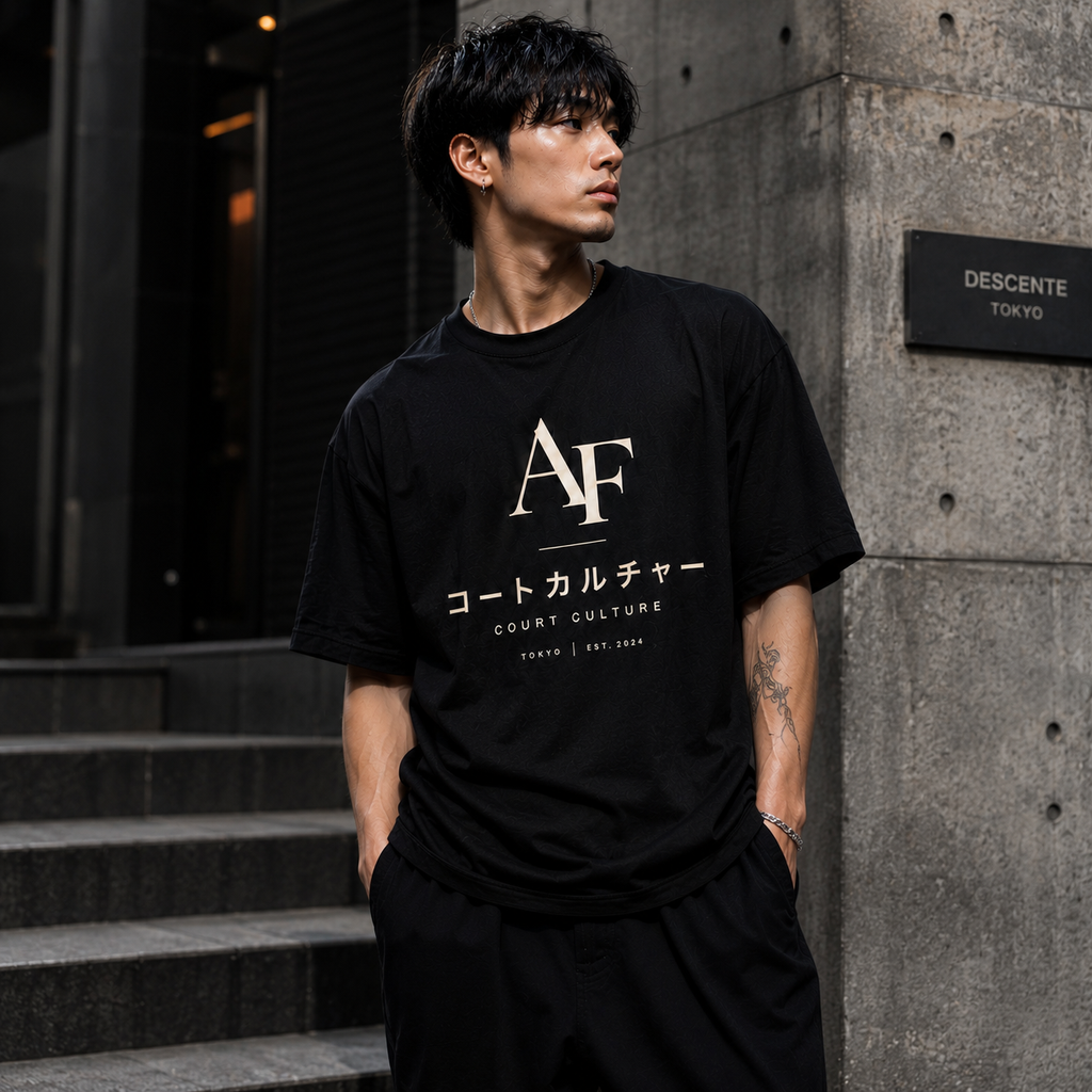 Man wearing a black t-shirt with 'AF' and Japanese text, standing against a concrete wall.