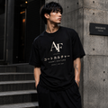 Man wearing a black t-shirt with 'AF' and Japanese text, standing against a concrete wall.