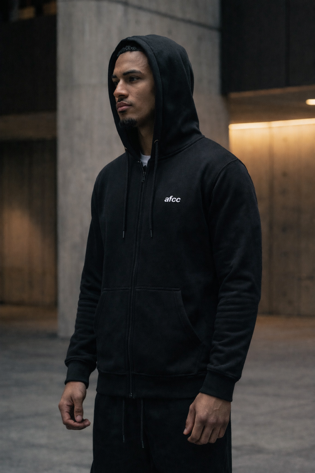 Person wearing a black hoodie with 'afcc' logo in an urban setting
