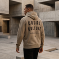 Person wearing a beige hoodie with 'Court Culture' text in an urban setting