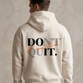 Person wearing a beige hoodie with 'DON'T QUIT. ACT. COUNT. WIN.' text on the back against a neutral background