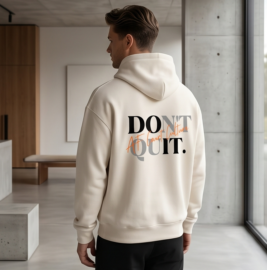 Person wearing a beige hoodie with 'Don't Quit' text in a modern indoor setting