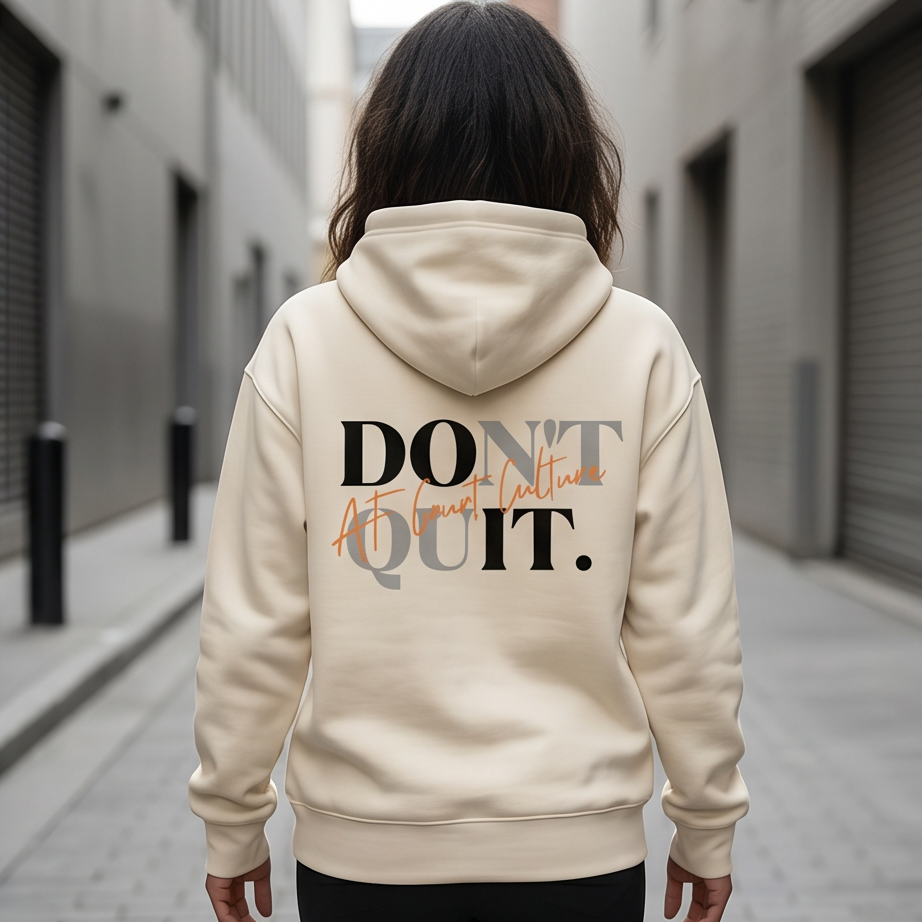Person wearing a beige hoodie with 'DON'T QUIT' text on the back in an urban setting