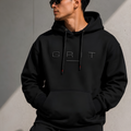 Person wearing a black hoodie with 'GRT' logo against a gray wall