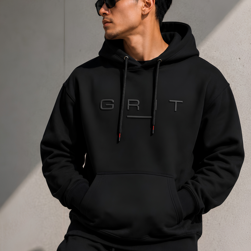 Person wearing a black hoodie with 'GRT' logo against a gray wall