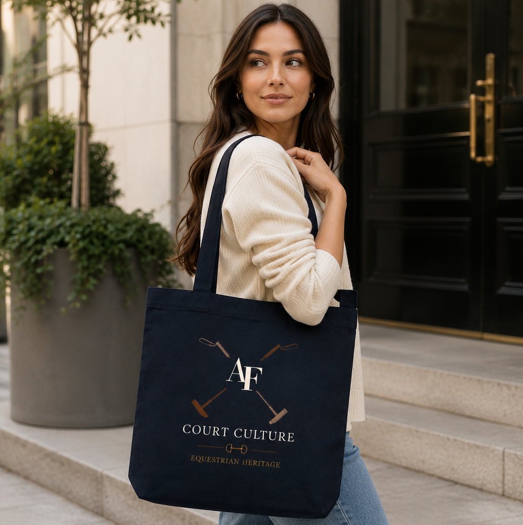 A woman wearing a cream sweatshirt and blue jeans carries a navy blue canvas tote bag with a gold and white 'Court Culture' logo, standing on stone steps in front of a building.