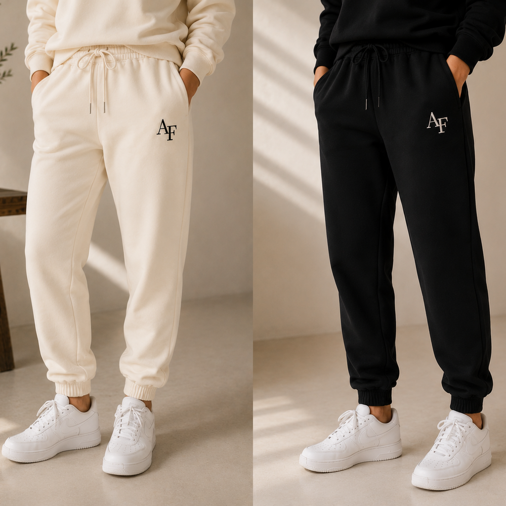 Two models wearing matching jogger sweatpants shown side by side, one in cream and one in black. Both pairs feature a drawstring waist, elastic cuffs, and an embroidered 'AF' logo on the left thigh.