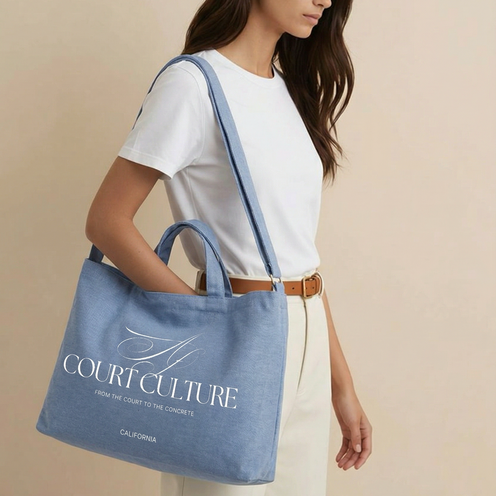 Woman holding a blue tote bag with 'Court Culture' branding against a beige background
