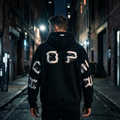 Person wearing a black hoodie with white text walking down a dark alley.