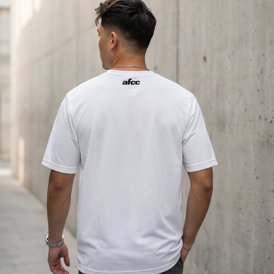 Person wearing a white t-shirt with 'afcc' logo on the back, standing against a concrete wall.
