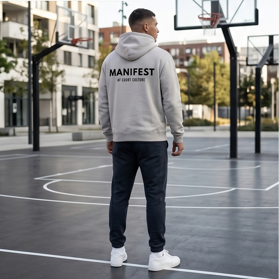 Person wearing a gray hoodie with 'MANIFEST' branding on a basketball court.
