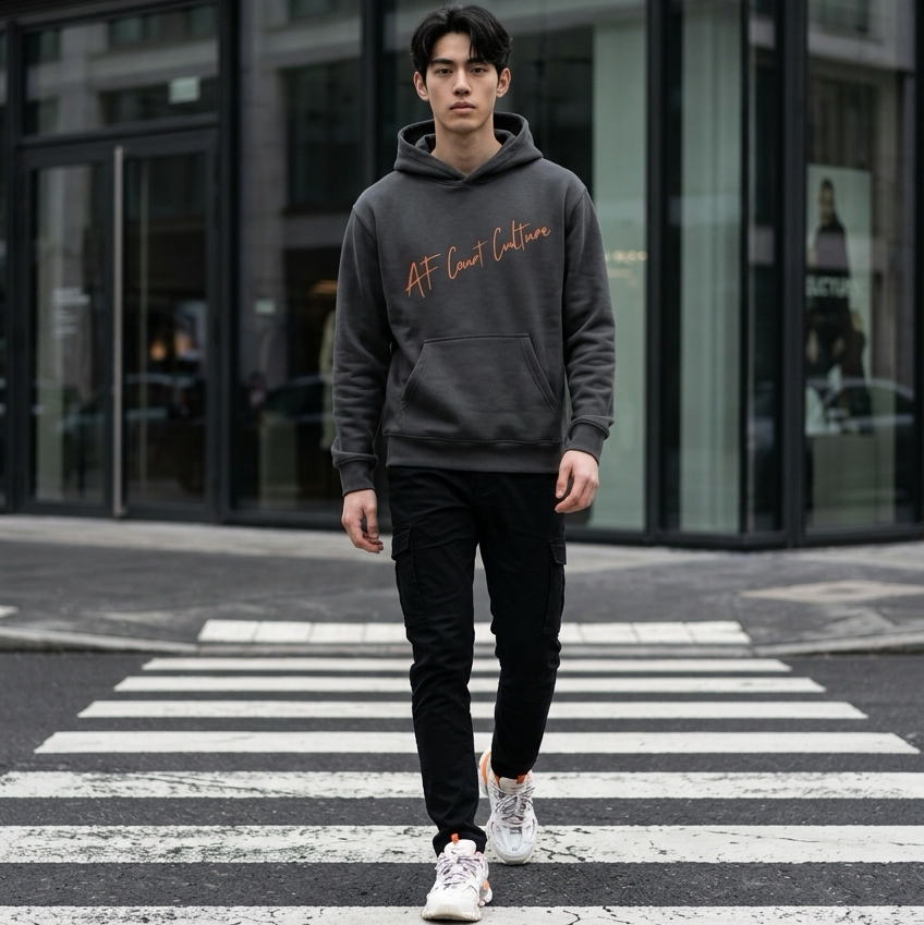 Man walking on a crosswalk wearing a dark hoodie and black pants.