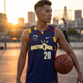 Person wearing a blue basketball jersey with 'Cactus Jack' and number '20', holding a basketball, against a cityscape background.