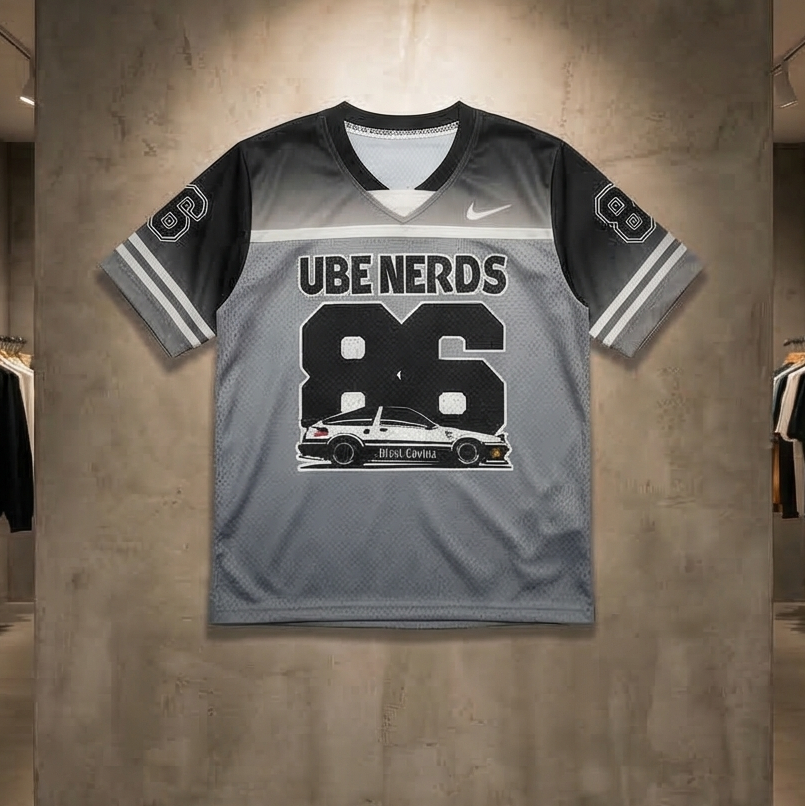 Gray sports jersey with 'UBE NERDS 86' printed on it, displayed against a concrete wall in a store.